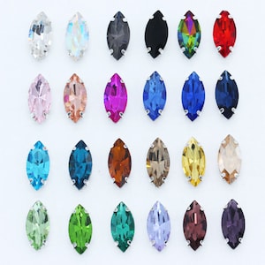 May include: Assortment of 20 marquise-shaped rhinestones in various colours, including clear, black, red, pink, blue, green, and brown. The rhinestones are arranged in rows on a white background.