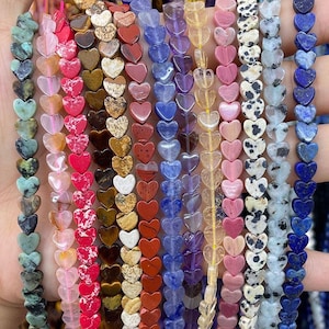 Peut inclure: Une collection de perles en forme de cœur, faites de pierres précieuses de différentes couleurs et motifs. Les brins comprennent des perles vertes, roses, rouges, marron, bleues et blanches. Les perles sont enfilées, créant un affichage attrayant de composants de bijoux en pierre naturelle.