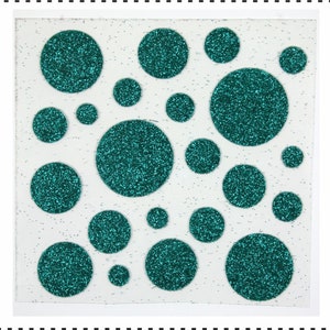 Op de afbeelding: Een vel wit papier met teal glittercirkels in verschillende maten.