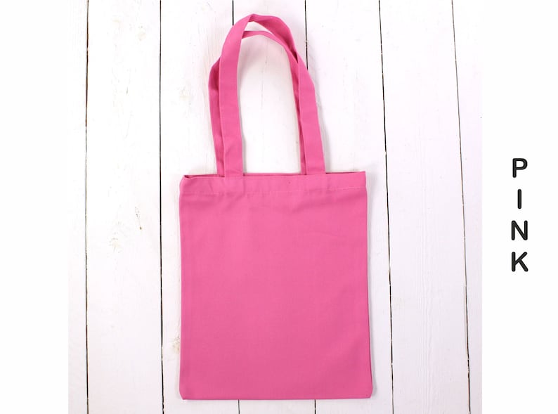 May include: A pink tote bag with two handles. The bag is made of a soft, cotton fabric.