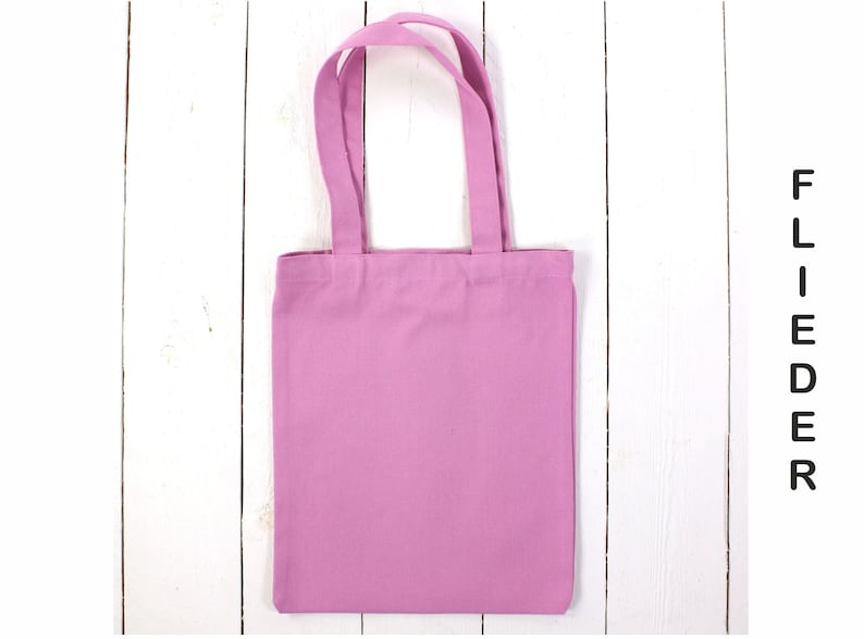 May include: A plain pink tote bag with fabric handles. The bag is made of a soft, cotton material.