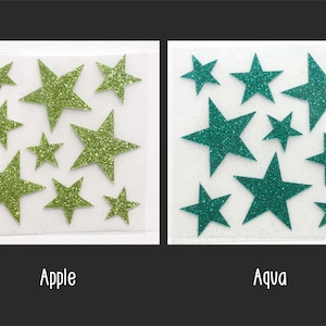 Op de afbeelding: Twee vellen wit papier met groene en turquoise glittersterren. Het vel links heeft het woord "Apple" eronder gedrukt. Het vel rechts heeft het woord "Aqua" eronder gedruckt.