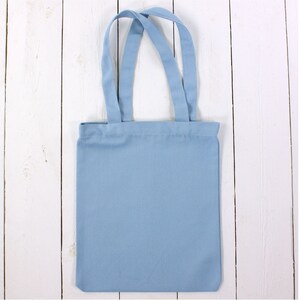 May include: A light blue tote bag with two handles. The bag is made of canvas and has a plain design.