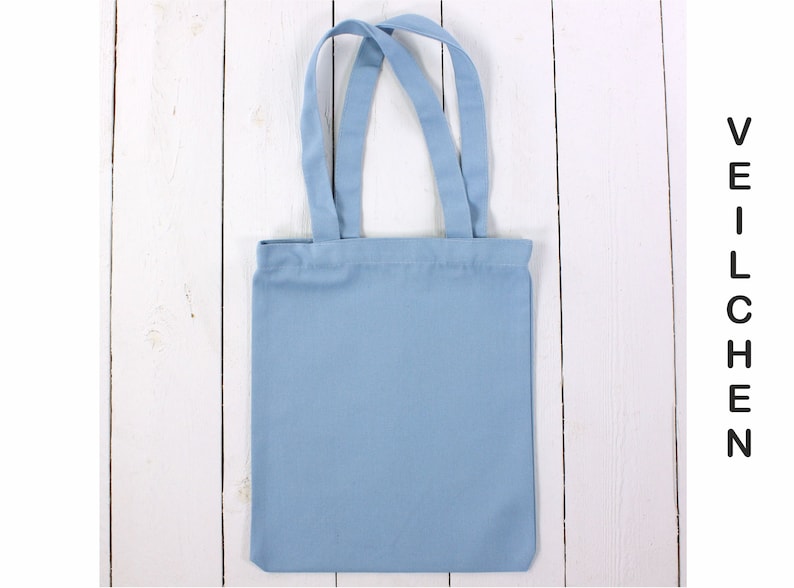 May include: A light blue tote bag with two handles. The bag is made of canvas and has a plain design.