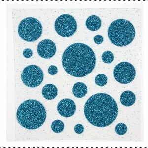 Op de afbeelding: Een vel wit papier met blauwe glitter stippen in verschillende maten. De stippen zijn in een willekeurig patroon gerangschikt.