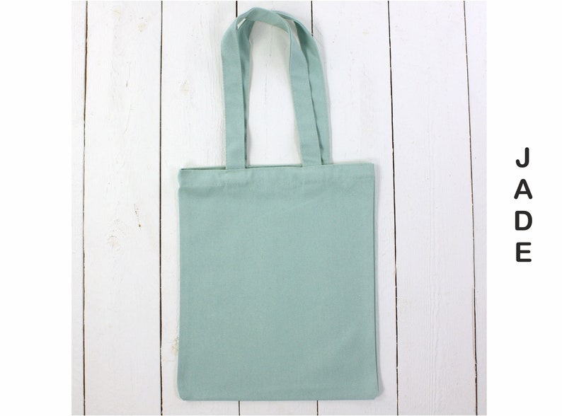 May include: A light green tote bag with two handles. The bag is made of canvas and has a plain design.