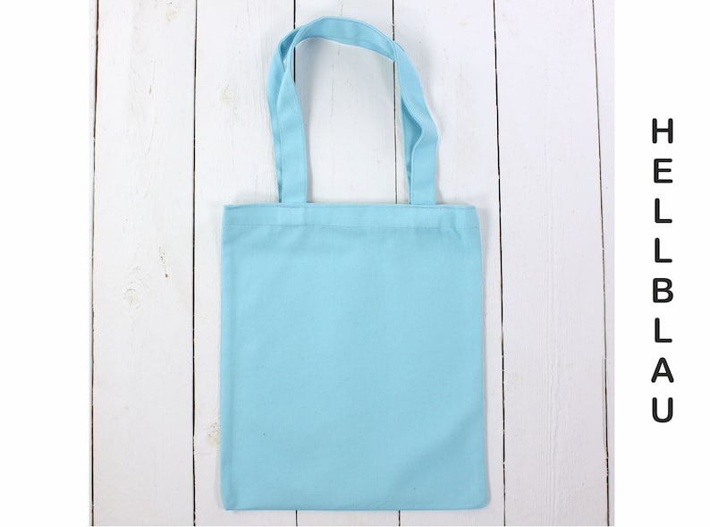 May include: A light blue tote bag made of cotton fabric. The bag has two handles and is empty.