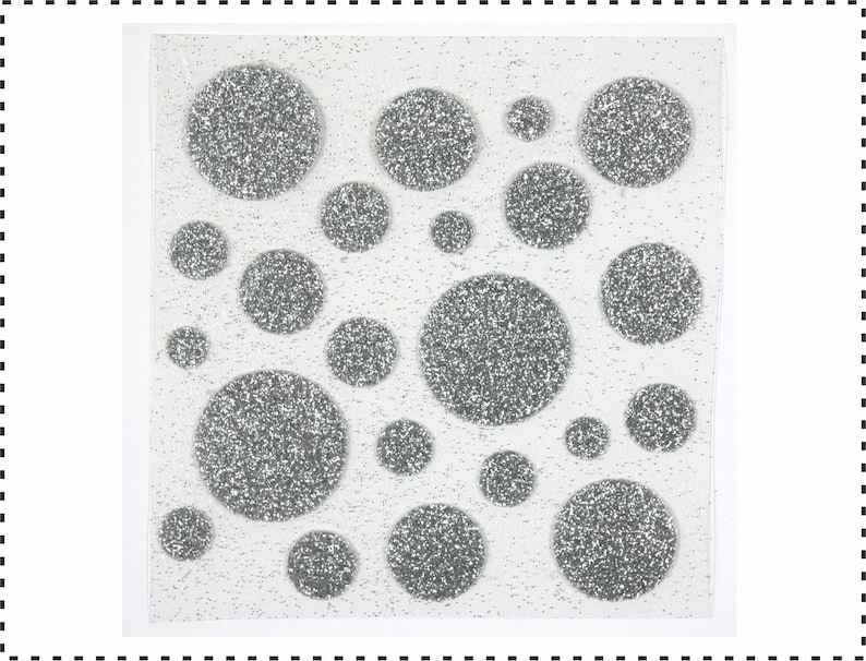 Op de afbeelding: Een vel met zilveren glitterlijm stippen in verschillende maten. De stippen zijn op een witte achtergrond.