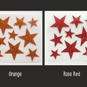 Op de afbeelding: Twee vellen met zelfklevende glittersterren, &eacute;&eacute;n vel is oranje en het andere is rozerood.