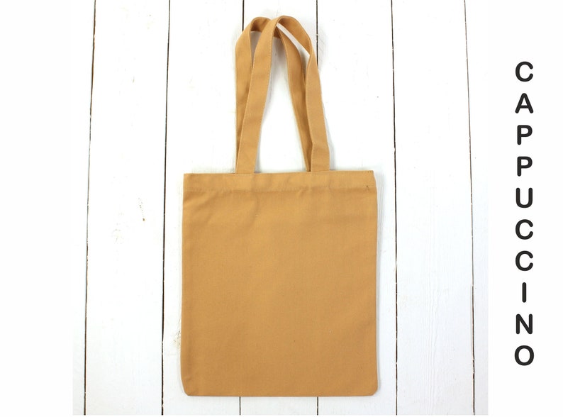May include: A plain, light brown tote bag with two handles. The bag is made of canvas and has a simple design.