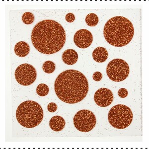Op de afbeelding: Een vel wit papier met 20 koperkleurige glittercirkels in verschillende maten. De cirkels zijn in een willekeurig patroon gerangschikt.