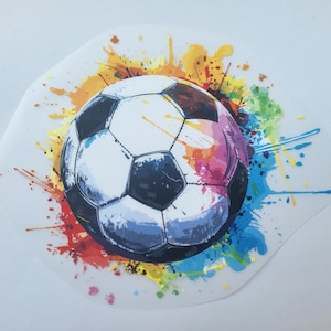 Könnte beinhalten: Ein weißer und schwarzer Fußball mit einem bunten Farbspritzer-Design. Die Farben umfassen Rot, Orange, Gelb, Grün, Blau und Lila.