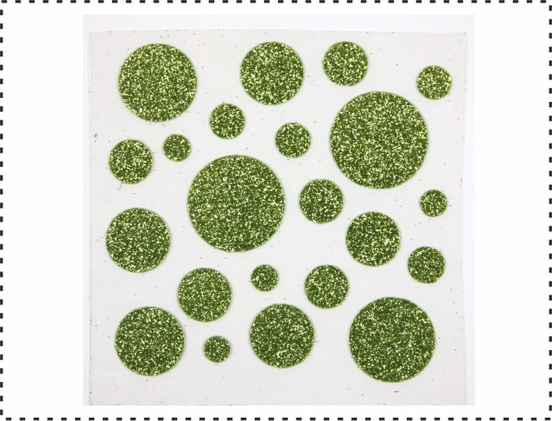 Op de afbeelding: Een vel met groene glitter stickers in verschillende maten en vormen. De stickers zijn op een witte achtergrond.
