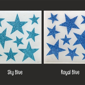 Op de afbeelding: Twee vellen wit papier met glittersterren. Het vel links heeft lichtblauwe sterren en het vel rechts heeft koninklijkblauwe sterren. De tekst "Sky Blue" staat onder het linker vel en de tekst "Royal Blue" staat onder het rechter vel.