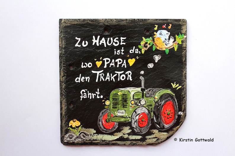 Puede incluir: Letrero de pizarra pintado a mano con un tractor verde y el texto "Zu Hause ist da, wo Papa den Traktor f&auml;hrt." Incluye detalles de p&aacute;jaros y flores. El letrero mide aproximadamente 20 cm de ancho y 18 cm de alto.