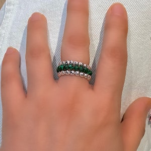 May include: A silver ring with three bands of small green and silver beads.