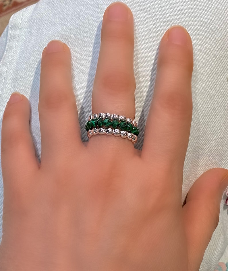 May include: A silver ring with three bands of small green and silver beads.