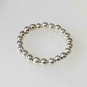 May include: A silver ring made of small, round beads.
