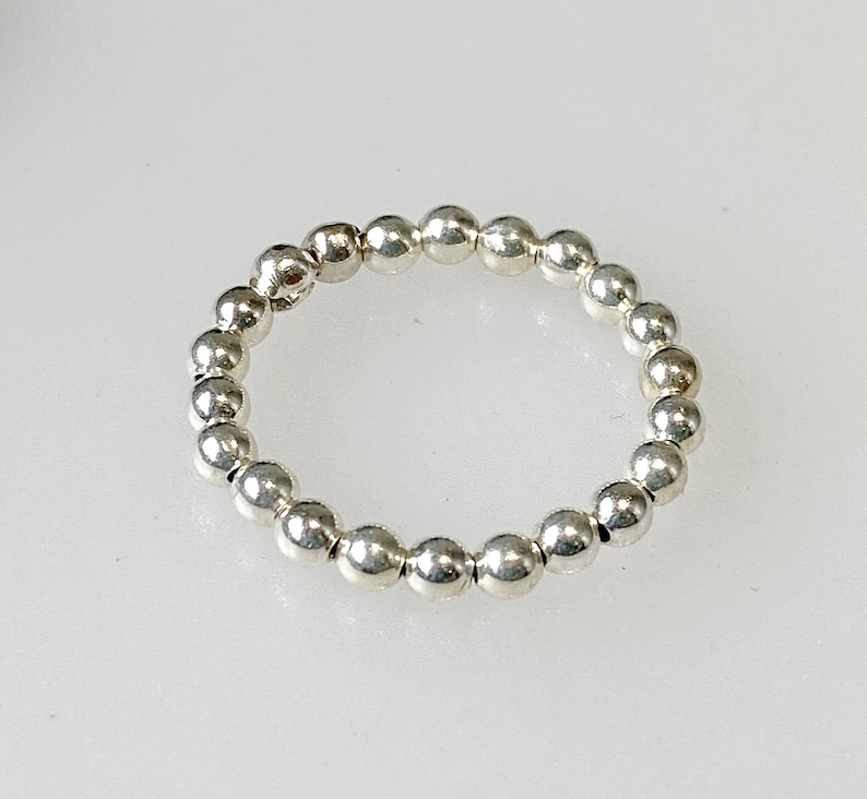 May include: A silver ring made of small, round beads.