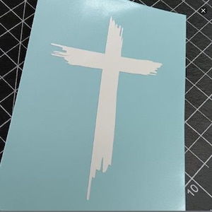 May include: A white cross with a distressed, brushstroke design on a light blue background.