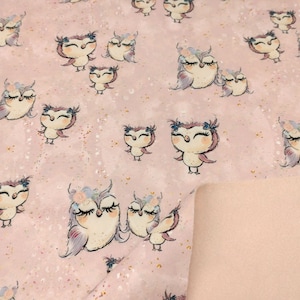 Op de afbeelding: Roze stof met een herhalend patroon van uilen met bloemenkransen. De uilen zijn getekend in een speelse stijl met grote ogen en worden in verschillende poses afgebeeld.