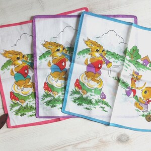 Könnte beinhalten: Set aus vier bunten Taschentüchern mit einem fantasievollen Design, das Hasen zeigt, die Musikinstrumente spielen. Die Taschentücher sind aus Baumwolle und haben einen weißen Hintergrund mit bunten Illustrationen.
