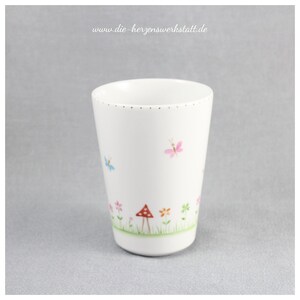 Puede incluir: Taza de cer&aacute;mica blanca con un borde dorado y un dise&ntilde;o caprichoso de mariposas, flores y un hongo. La taza est&aacute; decorada con un estilo delicado pintado a mano.