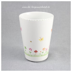 Puede incluir: Taza de cer&aacute;mica blanca con un dise&ntilde;o floral verde, rosa, amarillo y naranja. La taza tiene un borde dorado con puntos y el texto "www.die-herzenswerkstatt.de" est&aacute; impreso en el lateral.