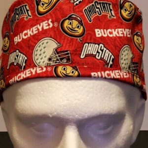 May include: Red and white scrub hat with a repeating pattern of Ohio State Buckeyes logos, a cartoon mascot, and football helmets.