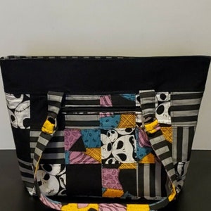 May include: Black tote bag with a patchwork design featuring a character from the Nightmare Before Christmas. The bag has yellow straps and a black zipper.