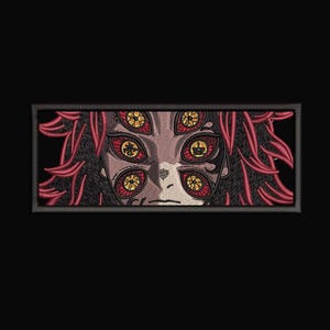 Peut inclure: Écusson brodé représentant le visage d'un personnage avec plusieurs yeux. Le design comprend des cheveux rouges et un teint neutre, sur fond noir. Les yeux sont jaunes et rouges.