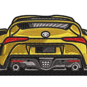 Może przedstawiać: Żółty samochód sportowy z czarnym tylnym spojlerem i czarnymi kołami. Samochód ma czarny tylny zderzak z czarnym dyfuzorem i dwoma rurami wydechowymi. Samochód ma czarny tylny uchwyt na tablice rejestracyjne i czarną tylną tablicę rejestracyjną. Samochód ma czarny tylny emblemat z logo Toyoty.