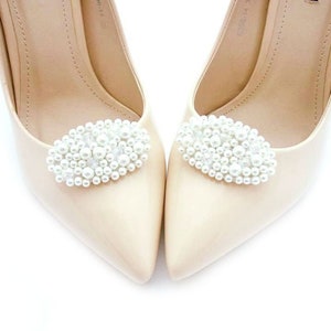 May include: A pair of beige high-heeled shoes with pearl embellishments on the toes.