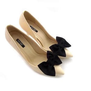 K&ouml;nnte beinhalten: Ein Paar nude High-Heel-Pumps mit schwarzen Schleifen an den Zehen. Die Schuhe haben den Markennamen "VICES" auf den Innensohlen.