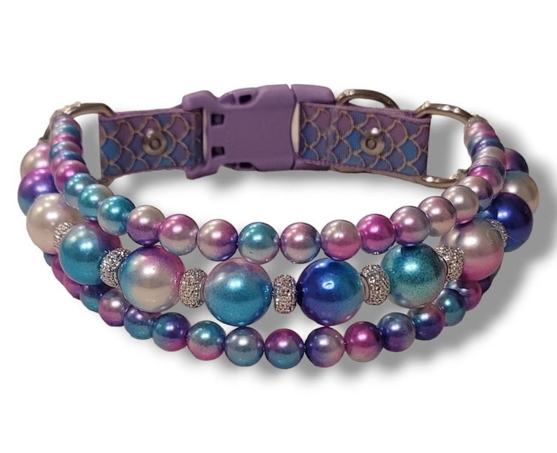 May include: A multi-strand dog collar with iridescent blue, pink, and white beads. The collar has a purple adjustable buckle.