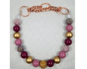 May include: A pink and burgundy beaded necklace with gold accents and a copper chain clasp.