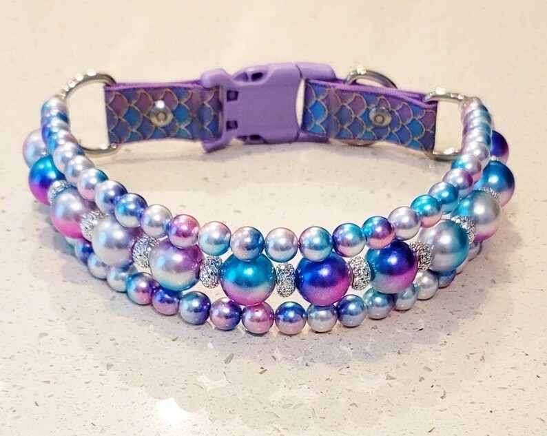 May include: A purple and iridescent dog collar with a mermaid scale pattern and three rows of iridescent pearls.
