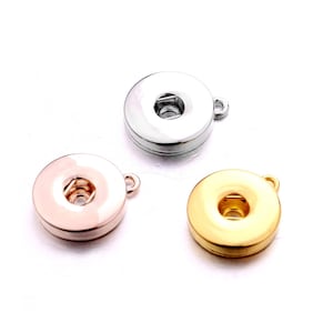 May include: Three round metal button charms with a loop for attaching to a necklace or bracelet. The charms are silver, gold, and rose gold.