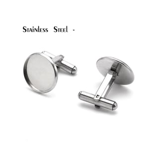 Könnte beinhalten: Ein Paar silberne Edelstahl-Manschettenknöpfe mit runden, flachen, silberfarbenen Einsätzen. "Stainless Steel" steht über den Manschettenknöpfen.