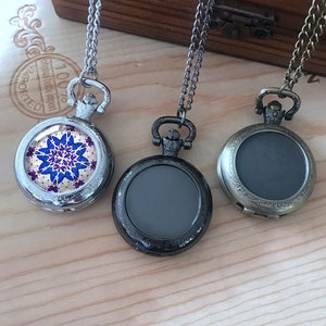 May include: Three silver pocket watches with chains. One watch has a colorful mandala design, while the other two have blank faces.