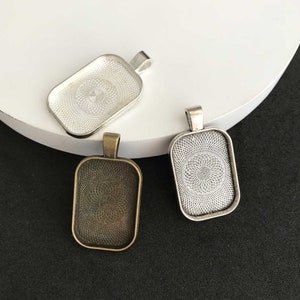 May include: Three rectangular pendant trays with a decorative pattern. The trays are silver, bronze, and antique silver.