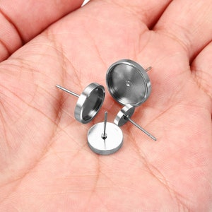 May include: Three silver earring settings with a round base and a post for attaching earrings. The settings are designed to hold a round cabochon.