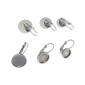 May include: Six silver-toned earring settings with a round bezel. The settings are designed to hold a round cabochon.