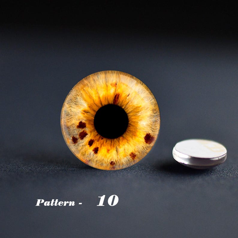 May include: A close-up of a yellow and brown eye-shaped design with a black center and dark spots. A small, round, silver-rimmed object is next to the eye design. The text "Pattern - 10" is at the bottom.