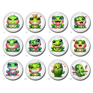 May include: A collection of twelve round, white-backed buttons featuring cartoon frogs and a cactus. The frogs are various shades of green with different expressions, including angry, winking, and smiling. One button features a cactus with a smiling face.