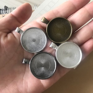 以下が含まれることがあります： 渦巻き模様の装飾が施された、銀と金のペンダントトレイ4つ。トレイは丸型で、上部に吊り下げ用のループが付いています。