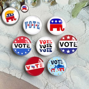 May include: A collection of political campaign buttons and a pendant. The buttons feature the word "VOTE" and elephant graphics in red, white, and blue. One pendant has an elephant graphic with a blonde hairstyle.