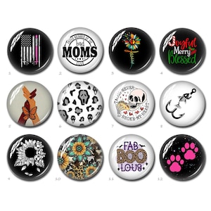 May include: Twelve round buttons with various designs. The designs include a US flag, a skull and crossbones, a butterfly, a sunflower, a ghost, a fish hook, a paw print, and a floral design. The buttons are all black and white with a glossy finish.