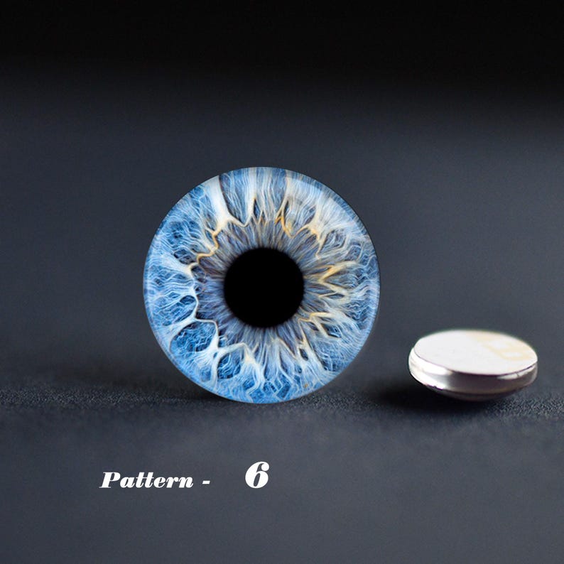 May include: A macro photograph of a blue eye with a black pupil and intricate patterns. The eye is next to a small, round, silver-rimmed object. The text "Pattern - 6" is at the bottom of the image.