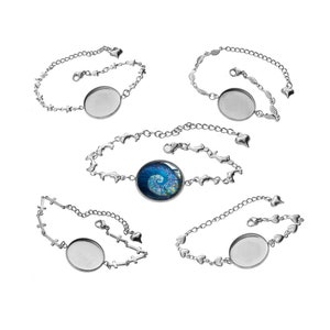 May include: Five silver-toned bracelets with different chain designs. Four bracelets have a blank, round setting. One bracelet features a blue and white spiral design. The chains include hearts, stars, crosses, and leaf-like shapes.